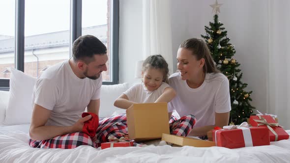 Happy Family with Christmas Gifts in Bed at Home alt