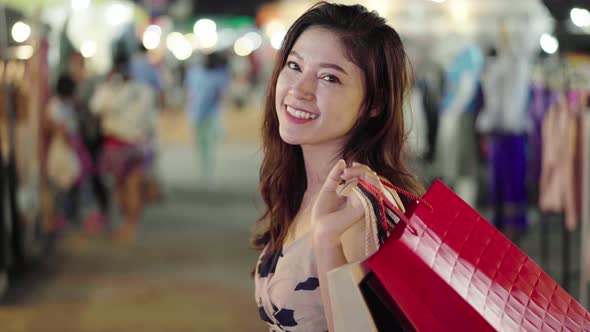 happy woman with shopping bags at outdoor night market