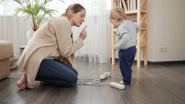 Mother telling her baby son not to play with electricity alt