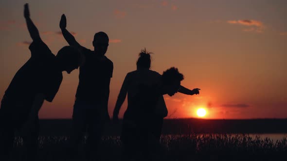 Silhouettes of Young People Have Fun at Sunset alt