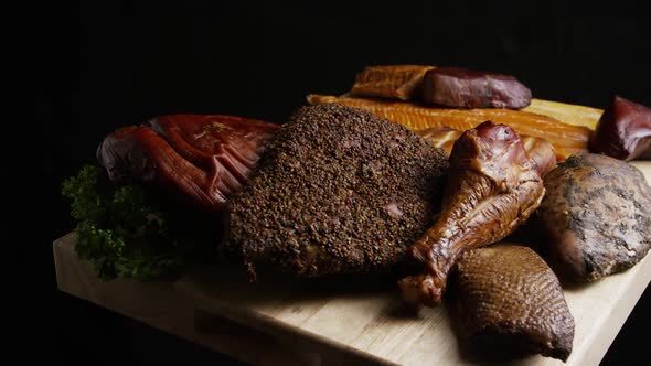 Rotating shot of a variety of delicious, premium smoked meats on a wooden cutting board  alt