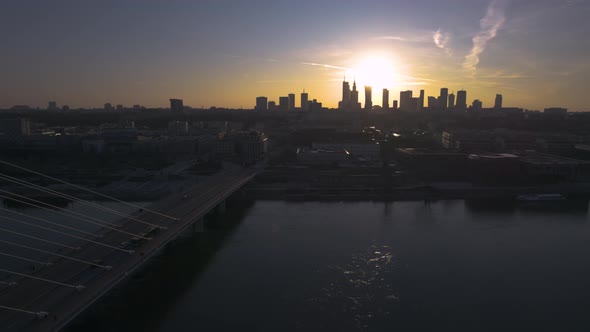 A rearward aerial drone shot of a sunset from Warsaw, the capital city and largest city in Poland. T alt