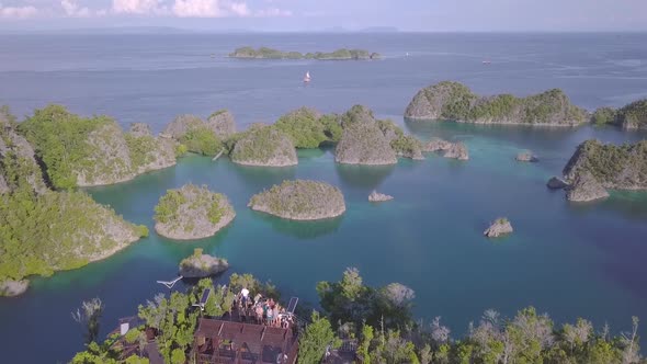 drone footage of a lagoon in Raja Ampat, Indonesia. showing people standing at a viewpoint looking o alt