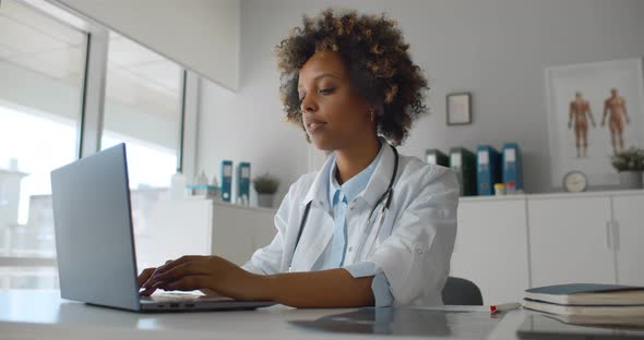 Young Afroamerican Female Doctor in Office Working on Laptop alt