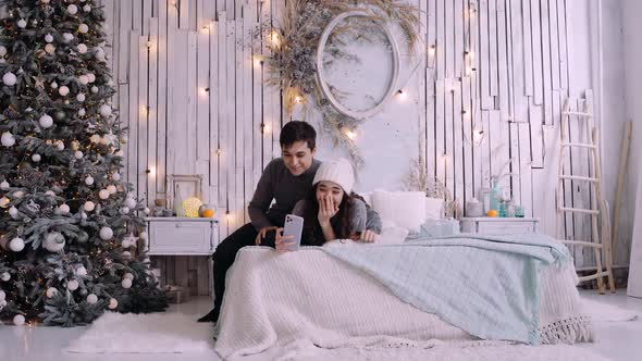 Young Couple Talking To Friends Using a Phone Because of the Covid 19. alt