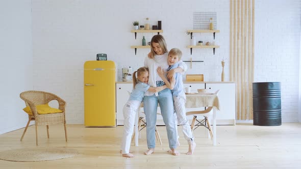 Two Children Son and Daughter Hug Their Mother Reaching Her Running