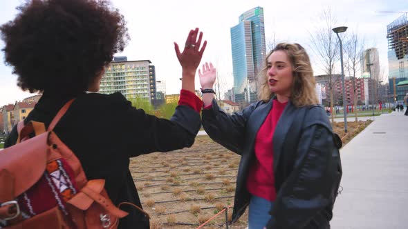 Women friends meeting outdoor in the city high five alt