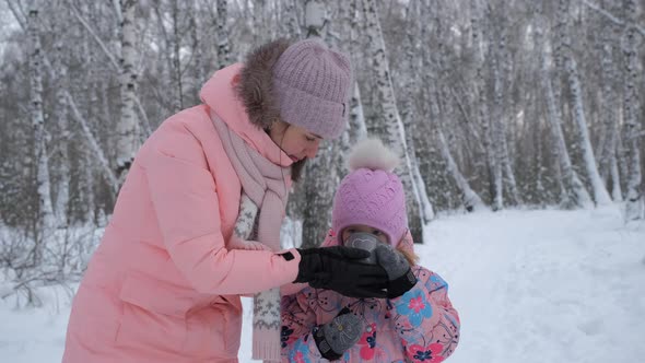 Mother Giving Hot Tea To Daughter in Winter Day alt