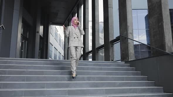 Young Beautiful Muslim Serious Woman Wearing Hijab Headscarf Walking Down Stairs Near Futuristic