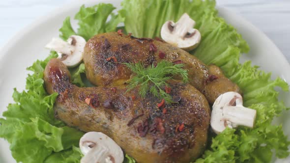 Fried Chicken Thighs Decorated with Mushrooms and Lettuce Rotate on a Plate alt