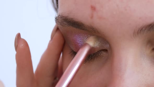 Professional Stylist Makeup Artist with a Brush Applies Shadows with Sparkles Making Bright Evening alt