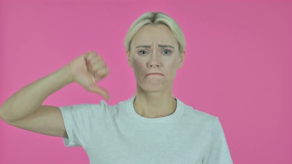 Young Woman Gesturing Thumbs Down on Pink Background alt