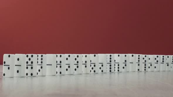 Domino Effect - a Series of White Dominoes Falling Down the Chain on Red Background alt