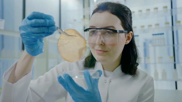 Close Up Portrait of a Woman Scientist in a White Coat with Tweezers in Her Hands Looking at alt