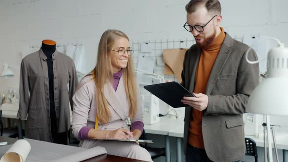 Tailoring Studio Employees Talking and Using Tablet Discussing Clothes Design Indoors alt
