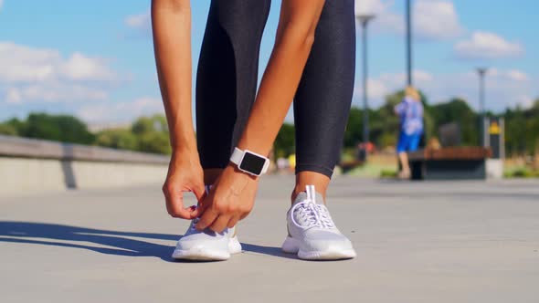Woman Tightening Sneakers and Running Outdoors alt