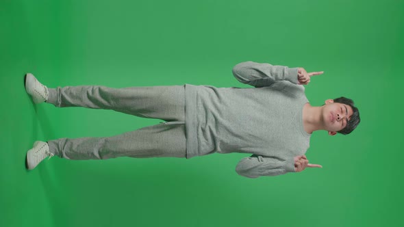 Full Body Of Asian Man Pointing Up While Standing In Front Of Green Screen Background alt