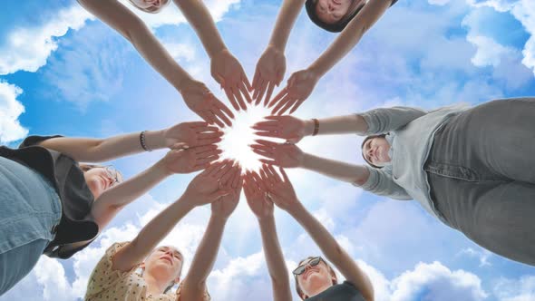Joyful Girls Pull Their Palms to the Center Against the Backdrop of a Fabulous Sky alt