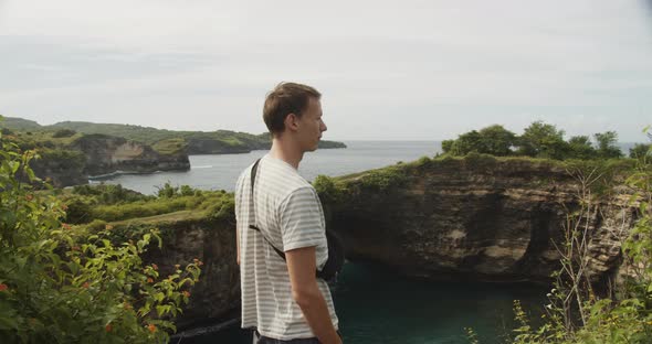 Close Up Shot Circling a Male Tourist with the Purse at the Cliff Above the Broken Beach on Nusa alt