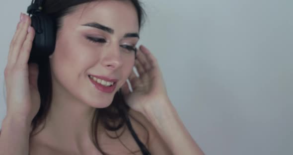 Happy Girl Holds the Earcups and Rejoices From Listening to Music in Headphones alt