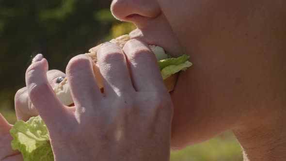 Woman biting off and chewing burger on the street