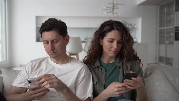 Newlyweds Relax Scrolling Through Social Media with Phones alt