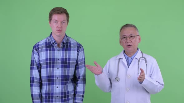 Stressed Mature Japanese Man Doctor with Young Man Explaining Something Together alt