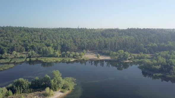 Camera Is Flying Over Amazing Calm River and Coast with Forest and High Trees
