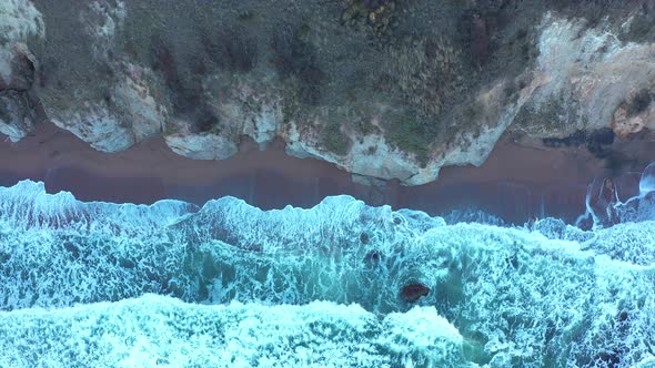 Aerial view to a beautiful wild rocky beach and big waves alt