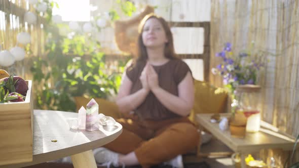 Young Woman Meditates on Sunny Terrace Focus on Crystals