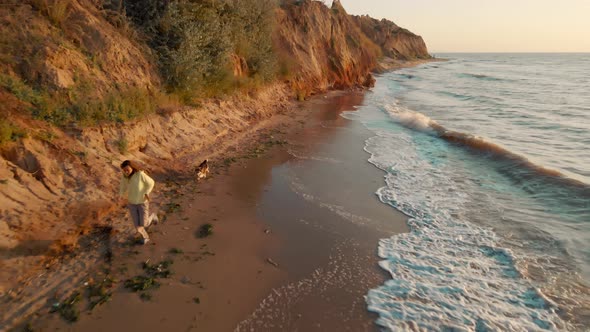 Woman Running By Beautiful Sandy Beach with Hills Along Sea Cute Dog Following for Girl alt