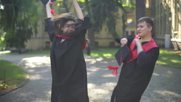 Satisfied Excited Graduates Dancing on Sunny Morning at University Campus Smiling alt