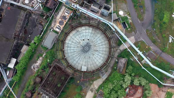 Aerial top-down view of storage tank at abandoned steel factory. Rotating high above alt