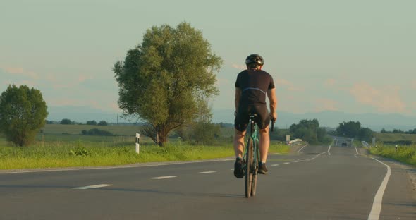 A Cyclist is Riding Along the Highway at a Slow Pace alt