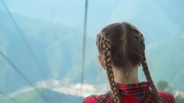 Adorable Happy Little Girl in the Cabin on the Cable Car in Mountains in the Background of Beautful
