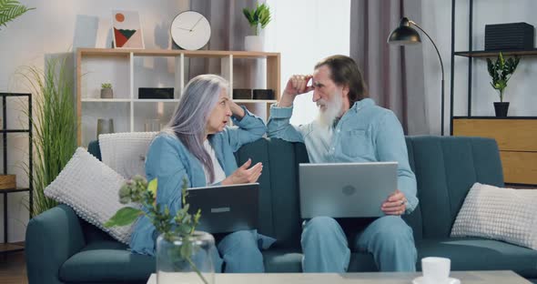 Old Bearded Man Talking with His Pretty Wife when they Together Sitting on Soft Couch alt