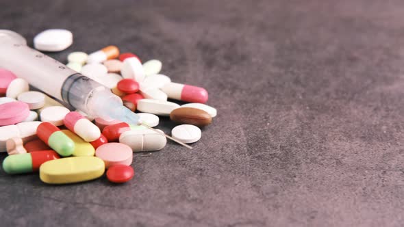 Syringe and Pills on Dark Background Close Up alt