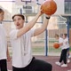 Handsome Male Coach Explaining to Child How to Put a Ball Into the Basket on Court Near School - VideoHive Item for Sale