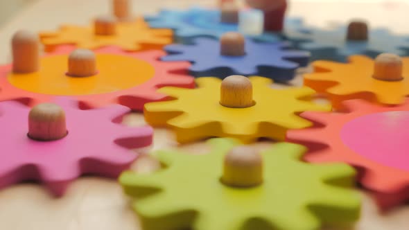 Turning Toy Wooden Gears. Gears and Cogs Macro in Colorful Wooden Toy. Side View. Team Work alt