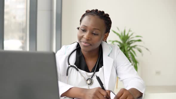 African Woman Doctor Having with Headset Chat or Consultation on Laptop alt