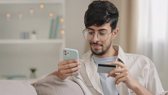Spaniard Arabic Young Man Guy with Glasses Sitting at Home Shopping Online Makes Internet Order Book alt