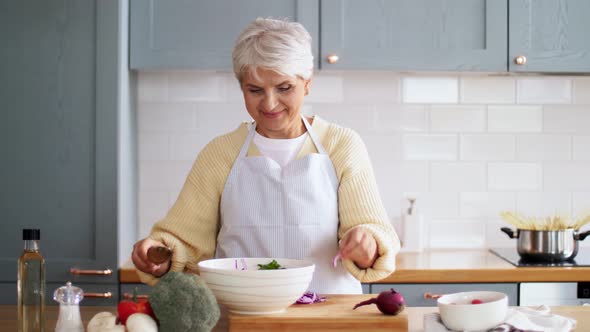 Happy Woman Cooking Vegetable Salad on Kitchen
