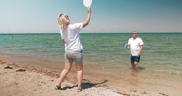 Man and Woman Playing Badminton on Beach alt