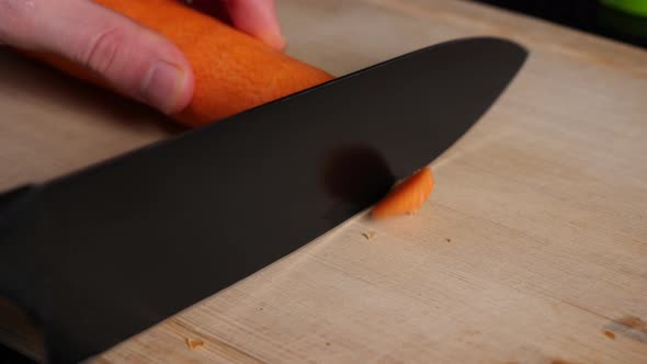 Cutting of the front and back of a carrot in slow motion on a chopping board. alt