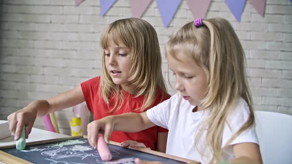 Cute Girls Drawing with Chalk on Blackboard alt