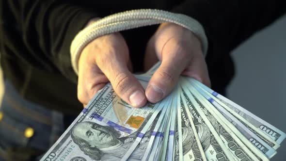 Male Hand Bound with the Rope Holding Pile of Money American Dollar Bank Notes, Financial