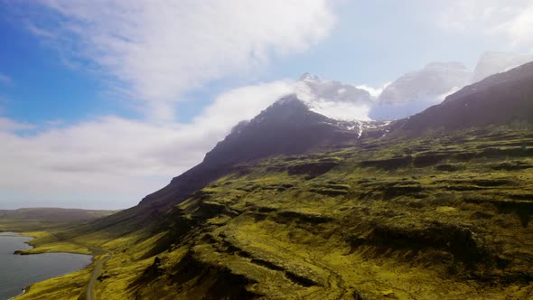 Aerial Shot of Mountain Summit with Snow Road and Sky in Background alt