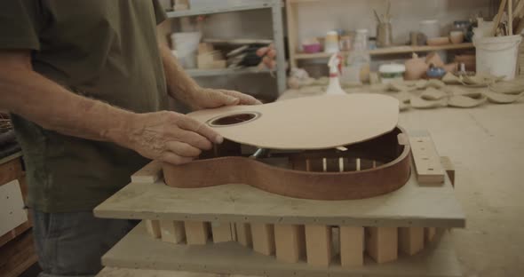 Luthier places a wooden part on a guitar mold