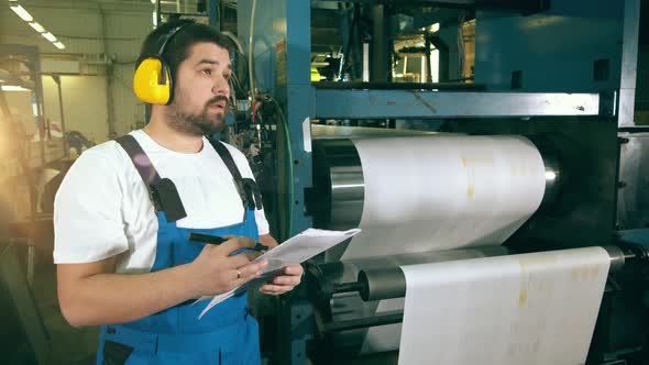 Male Engineer, Constructor and a Paper-rolling Conveyor alt
