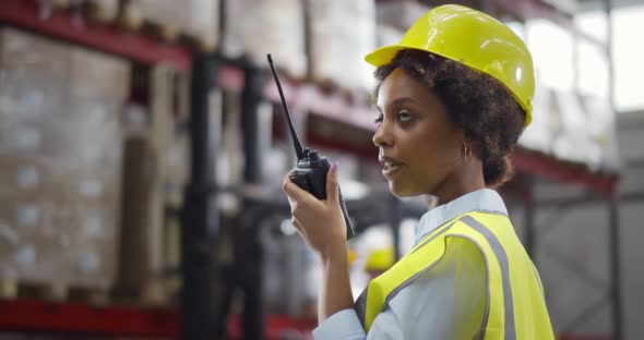 AfroAmerican Female Worker of Warehouse Reporting Through Walkietalkie alt